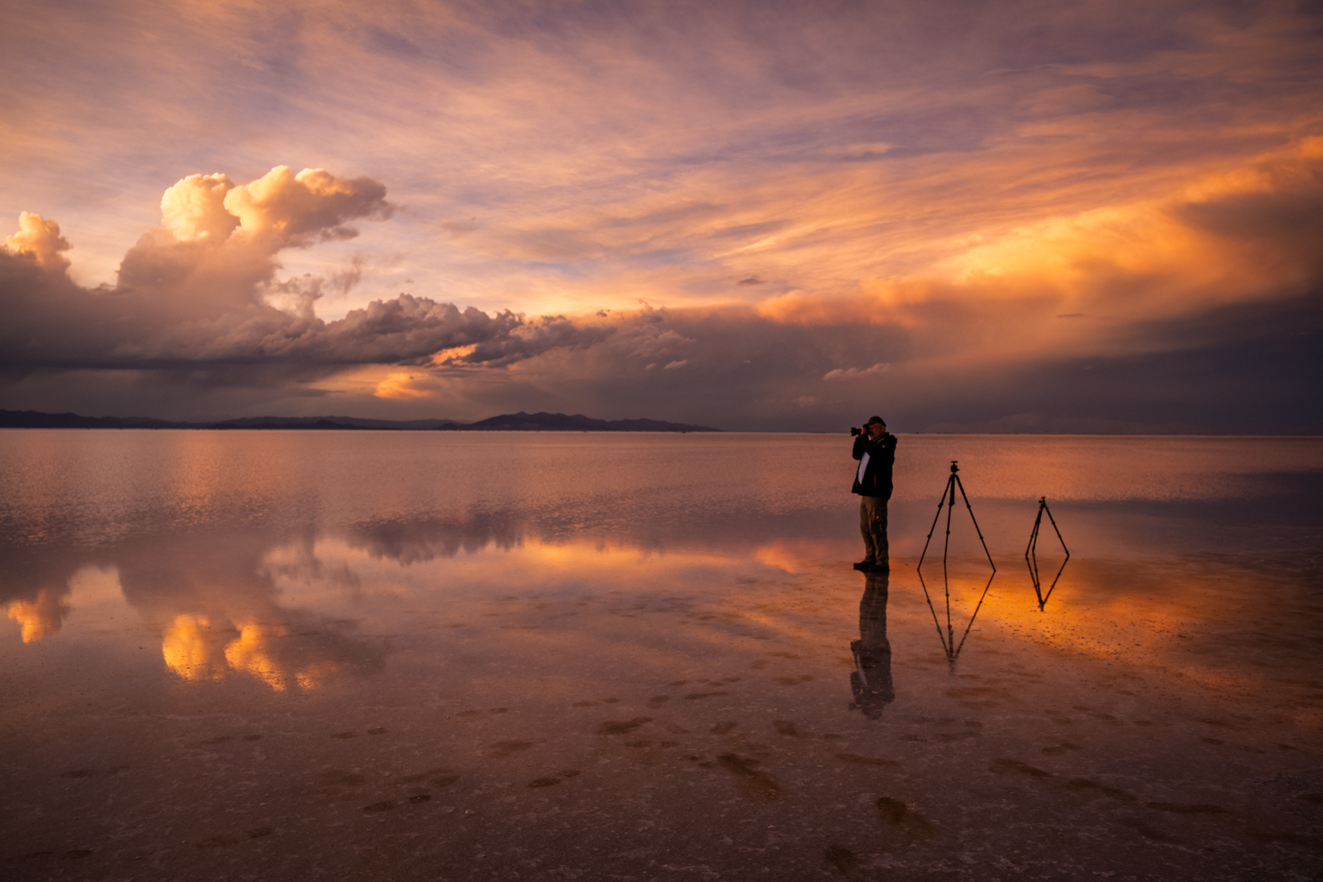 Fotograf auf dem spiegelnden Salzsee unter dramatischem Abendhimmel.